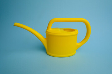 Yellow watering can on a blue background. Isolated.