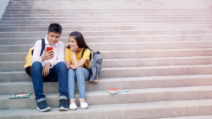 asian teenagers friendship sitting on stair in the garden and looking mobile phone