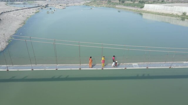 Drone flies high in the sky above floating clouds. Below, overlooks an impressive view of the Hanging bridge near machhu dam, Aerial. 4K