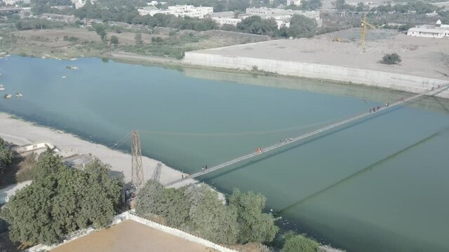 Drone flies high in the sky above floating clouds. Below, overlooks an impressive view of the Hanging bridge near machhu dam, Aerial. 4K