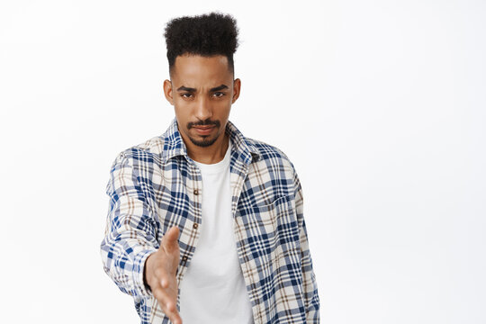 Serious and confident young african american man stretch out hand for handhsake, frowning and looking determined, greeting people, attend business meeting interview, white background