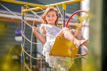 Laughing child girl on swing at playground