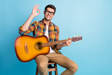 Photo of dreamy attractive gentleman wear checkered shirt holding guitar showing okey empty space isolated blue color background