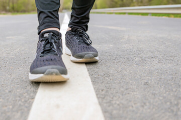 Morning run. Running feet while running, Runner in black sneakers runs on the asphalt.