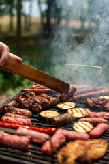 Assorted delicious grilled meat with vegetables over the coals on a barbecue. Closeup of steak barbecues cooking grilling on charcoals. Vertical