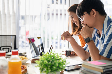 Friendly asian business team colleagues eating pizza and potato chips together in office have fun talk enjoy corporate party