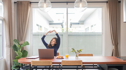 Work from home concept a female entrepreneur being relaxed stretching her arms while working remotely in her house