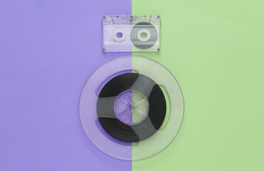 Retro flat lay. Audio magnetic tape reel and audio cassette on colored pastel background. Top view....