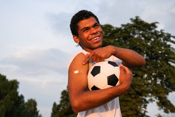 Young Afro American sportsman showing his arm after receiving vaccine at sunset