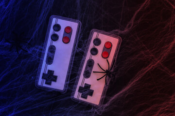 Old retro gamepads on a black background with cobwebs and spiders. Halloween theme. Arachnophobia. Neon light © splitov27