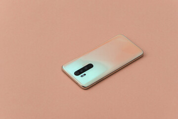Modern smartphone back with lenses on orange background.