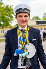 Closeup outdoor summer portrait of a young man at a graduation ceremony with student hat.