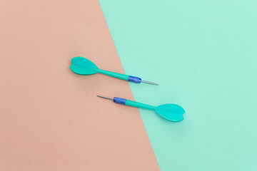 Two plastic darts with metal tip on pink blue pastel background. Top view. Flat lay. Minimalism
