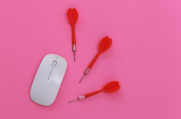 Pc mouse and darts on pink background. Top view