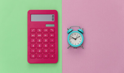 Calculator and alarm clock on pink green pastel background. Top view. Flat lay