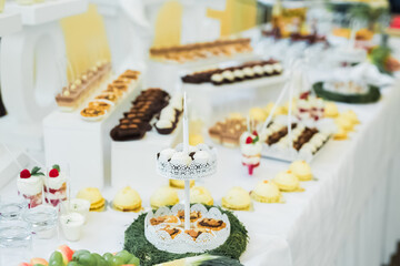 Delicious sweets on wedding candy buffet with desserts, cupcakes