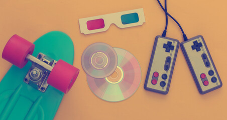 Retro entertainment, gadgets and devices. Gamepads, cruiser board, Cd's, 3D glasses on yellow...
