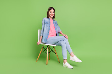 Fototapeta na wymiar Full length photo of nice brunette hair millennial lady sit wear jeans jacket isolated on green color background