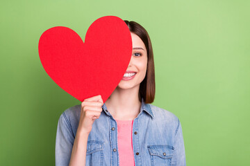 Photo of young girl happy positive smile cover close face big red paper heart love isolated over green color background