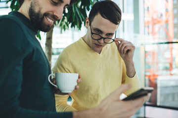 Positive diverse colleagues chatting on smartphone