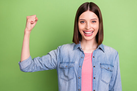Photo of funky brunette hair young lady show biceps wear jeans jacket isolated on green color background