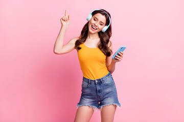 Photo of adorable sweet young woman wear yellow singlet listening music holding modern gadget...