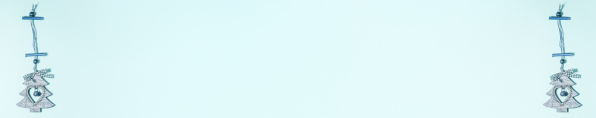 Banner of flat lay of wooden christmas decoration tree with heart inside it and jingle bell on blue on the left and right side. Christmas holidays concept from above with copy space
