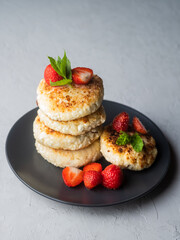 Cottage cheese pancakes with strawberries, mint and sour cream on a light background. syrniki. healthy dessert