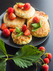 Cottage cheese pancakes with strawberries, mint and sour cream on a black background. syrniki. healthy dessert