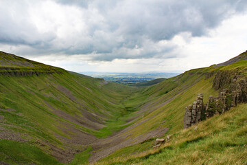 View of mouth of High Cup Nick a U-shaped valley in the northern Pennines in Cumbria, England, with the grey-blue dolerite crags seen on the right hand side - obrazy, fototapety, plakaty