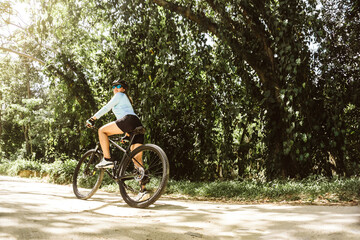Latin American woman with helmet and glasses riding a mountain bike on a dirt road. routes, adventure and nature concept. taking a break on road.