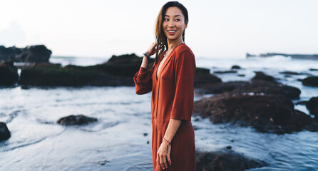 Smiling woman standing outside rocky coast