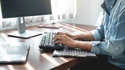 Asian woman programmer looking on keyboard to typing code data about new project on laptop while working