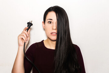 A brunette young girl holding an electrical plug. European type c plug