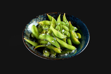 Edamame bean salad with sea salt served in a dark bowl. Isolated on a black background. Restaurant food. Japanese kitchen