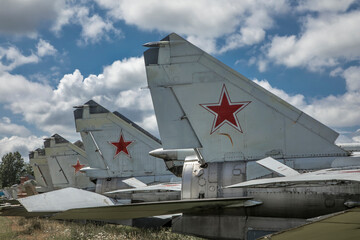 Tails of old abandoned aircraft. Old rusty airplanes with red stars on their tails. Sunny day. Old military aircraft.