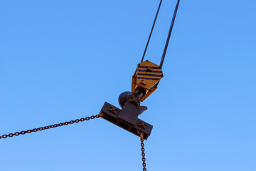 Obraz premium Slings and hook of a construction crane against a blue sky. Industrial background