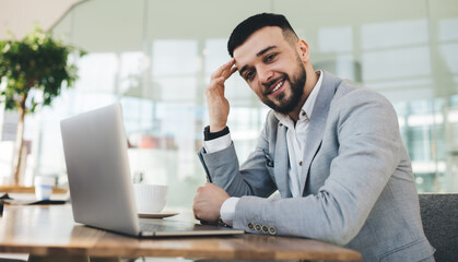 Fototapeta na wymiar Smiling male entrepreneur working on laptop in modern workspace