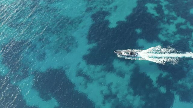 Speed boat cruising in blue Aegean sea, Greece, Cyclades. Aerial drone video, footage 4k. Wake on calm sea surface, 