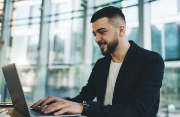 Positive businessman surfing laptop in cafe