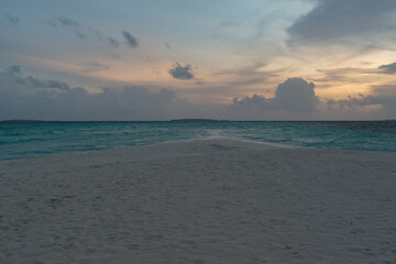 Obraz premium sandy coast of a coral island in the Indian Ocean at sunset in cloudy weather