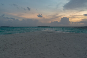 sandy coast of a coral island in the Indian Ocean at sunset in cloudy weather