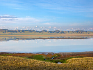Panoramic view of Lake Tuzkol Lake with a spring in the foreground and Khan Tengri peak on the horizon. Kazakhstan