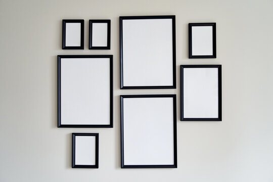 Different size framed photos hanging on the gray wall. Mockup.