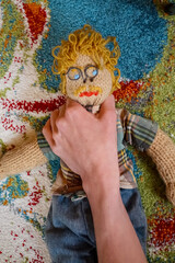Eine männliche Strickpuppe wird von einer Hand gewürgt und festgehalten. Dem Typ geht es an den...