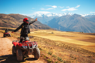a person on a red quad happy looking to a beautiful view and rising a hand - obrazy, fototapety, plakaty
