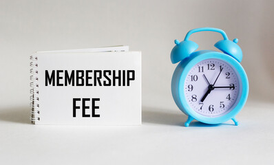 On notepad text about membership fee, business concept image on white background with alarm clock