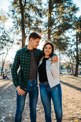 Obraz premium young couple backlit in a square, with a sunset in the background, wearing casual clothes