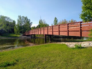 Fototapeta na wymiar Panoramic view of a wooden, brown bridge with railings across the river.