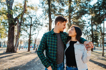 young couple backlit in a square, with a sunset in the background, wearing casual clothes